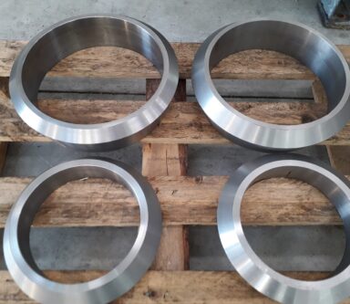 Anelli metallici di precisione posizionati su pallet, pronti per l'assemblaggio industriale.