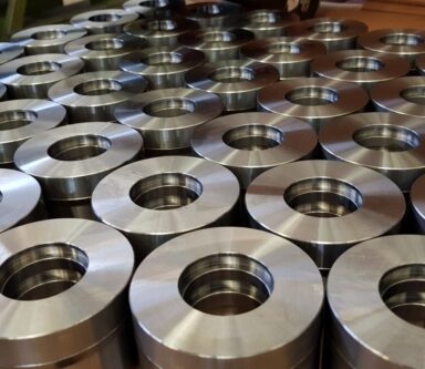 Pezzi cilindrici in acciaio inox disposti ordinatamente, utilizzati in meccanismi di precisione.