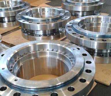 Grandi flange lucide impilate, pronte per l'assemblaggio in strutture industriali robuste.