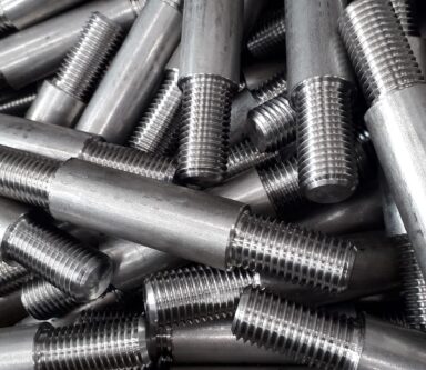 Connettori filettati in acciaio grezzo su una superficie in legno, pronti per assemblaggi di alta precisione.
